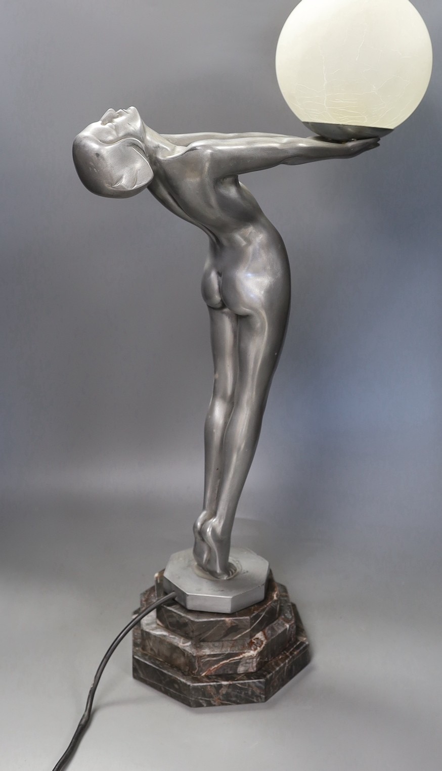 An Art Deco style figurative lamp of a lady holding a frosted glass globe, 66cms high.